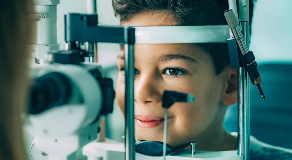 Functional Vision Assessment. A young boy smiles as an Ophthalmologist examines his eyes.