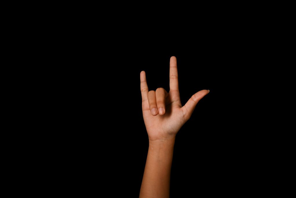 Sign Language Interpreters help others express themselves. A hand is signing the I love you sign.